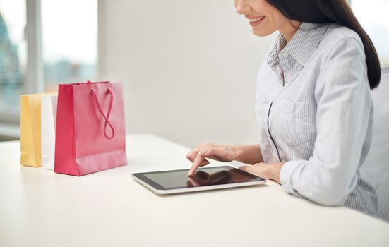 business, technology, sale, communication and people concept - close up of woman with tablet pc computer and shopping bags at office or home