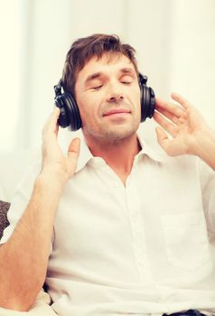 leisure and lifestyle concept - happy man with headphones listening to music at home