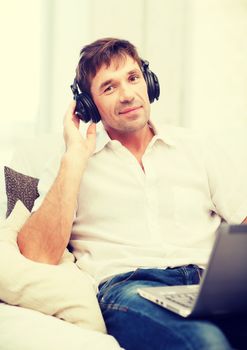 technology, leisure and lifestyle concept - happy man with headphones listening to music at home