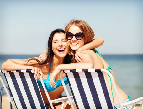 summer holidays and vacation - girls in bikinis sunbathing on the beach chairs