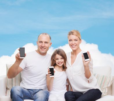 family, technology, advertisement and people concept - smiling mother, father and little girl with smartphones over blue sky and white cloud background