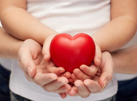 people, charity, family and advertisement concept - close up of woman and girl holding red heart shape in cupped hands