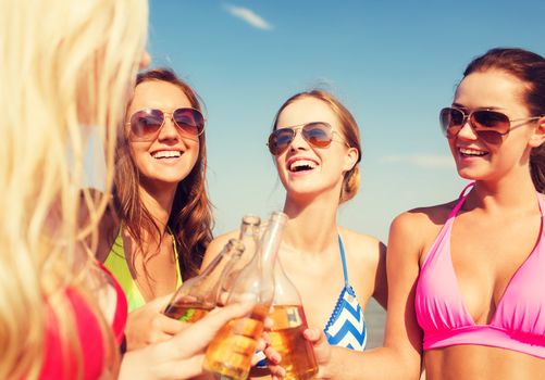 summer vacation, holidays, travel and people concept - group of smiling young women sunbathing and drinking on beach