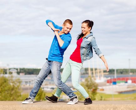 summer holidays, teenage and dancing concept - couple of teenagers dancing outside