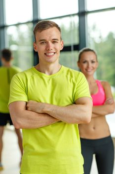 sport, fitness, lifestyle and people concept - smiling man and woman in gym