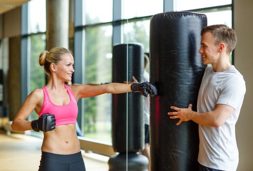 sport, fitness, lifestyle and people concept - smiling woman with personal trainer boxing in gym