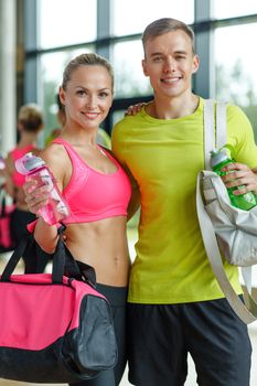 sport, fitness, lifestyle and people concept - smiling couple with water bottles in gym