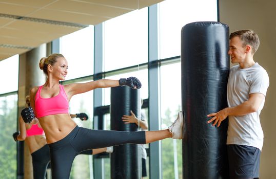 sport, fitness, lifestyle and people concept - smiling woman with personal trainer boxing in gym