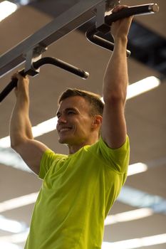 sport, fitness, lifestyle and people concept - smiling man doing pull-ups in gym