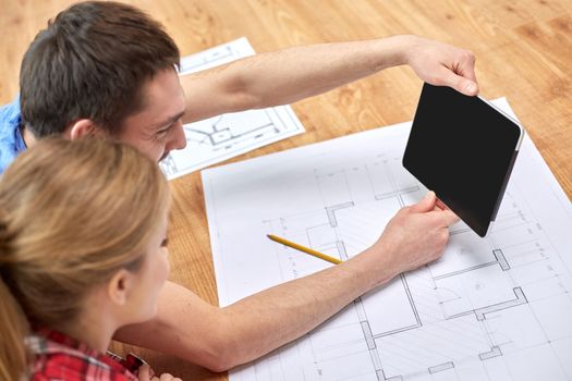 repair, building, renovation, architecture and technology concept - close up of couple with tablet pc computer blank screen and blueprints at home