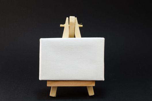 Miniature artist easel, isolated on black background.