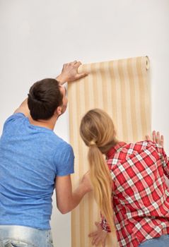 repair, renovation, building and people concept - close up of couple holding wallpaper at home