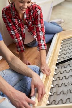 people, moving and furnishing concept - close up of couple assembling furniture at home