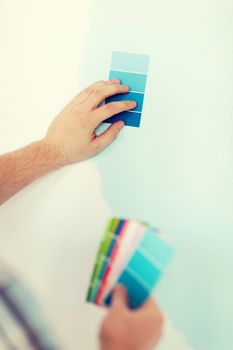 repair, building, technology and home concept - close up of male with color pallets choosing color