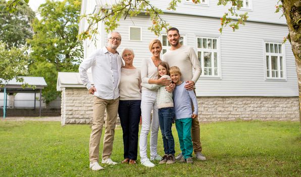 family, happiness, generation, home and people concept - happy family standing in front of house outdoors