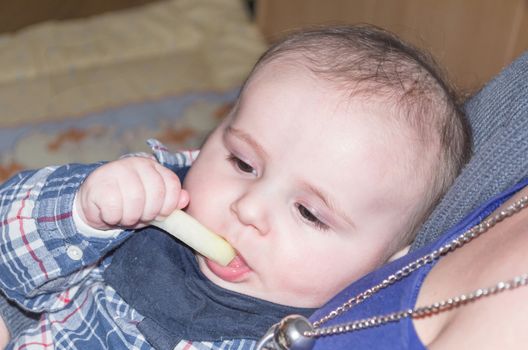 Portrait of a happy little boy.   Baby on the mother's arms. The toddler is eating.