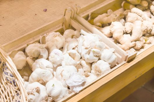 Many Italian garlic onions and ginger root for sale at a farmers market.
