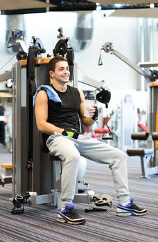 sport, fitness, equipment, lifestyle and people concept - smiling man exercising on gym machine