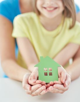 people, charity, family and home concept - close up of woman and girl holding green paper house cutout in cupped hands