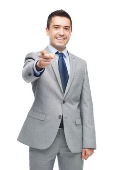 business, people and office concept - happy smiling businessman in suit pointing at you