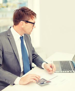 business, office, school and education concept - businessman with laptop computer, papers and calculator