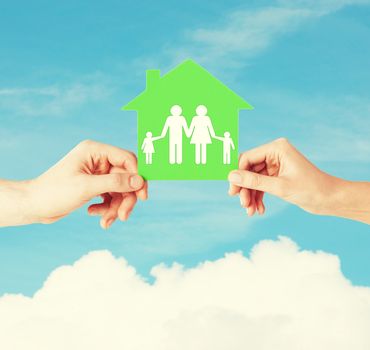 real estate and family home concept - isolated picture of male and female hands holding green paper house with family