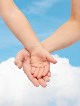 people, charity, family, children and advertisement concept - close up of woman and little child hands holding empty palms over blue sky and cloud background