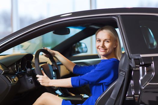 auto business, car sale, consumerism , transportation and people concept - happy woman sitting inside car in auto show or salon