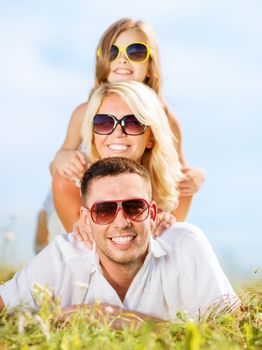 summer holidays, children and people concept - happy family with blue sky and green grass