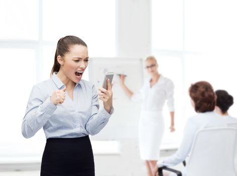 business, technology and education concept - screaming businesswoman with smartphone in office