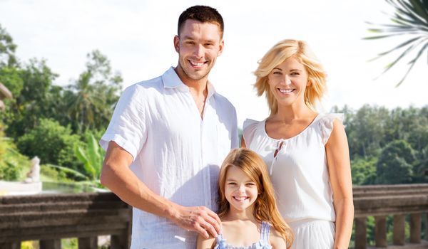 summer holidays, travel, tourism and people concept - happy family on vacation over villa balcony background