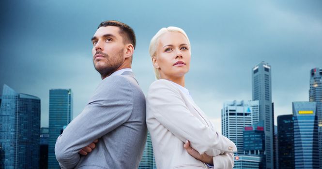 business, partnership, teamwork and people concept - businessman and businesswoman standing over city buildings background