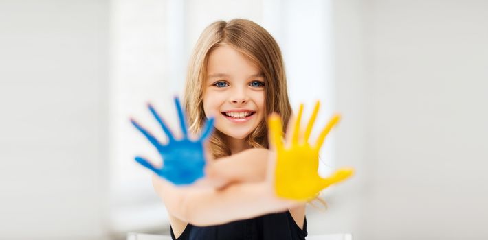 education, school, art and painitng concept - little student girl showing painted hands at school