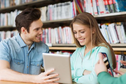 people, education, technology and school concept - happy students with tablet pc computers networking in library