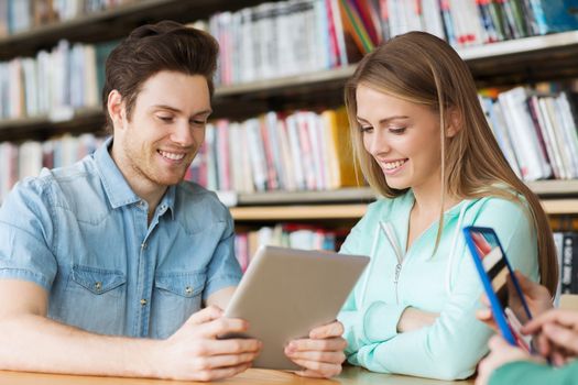 people, education, technology and school concept - happy students with tablet pc computers networking in library