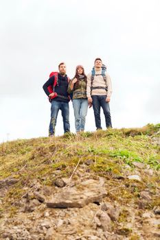 adventure, travel, tourism, hike and people concept - group of smiling friends with backpacks outdoors