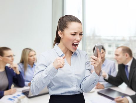 business, technology and education concept - screaming businesswoman with smartphone in office