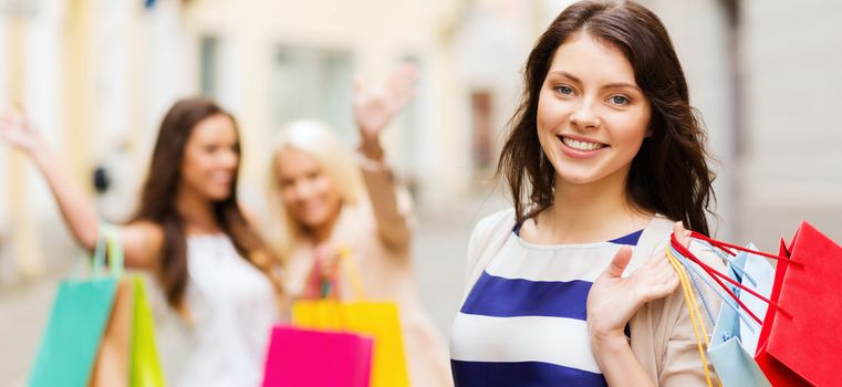 shopping and tourism concept - beautiful girls with shopping bags in ctiy