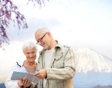 family, age, tourism, travel and people concept - senior couple with map and city guide over japan mountains background
