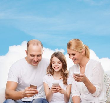 family, technology and people - smiling mother, father and little girl with smartphones over blue sky and white cloud background