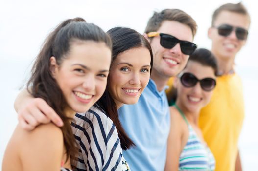 summer holidays, vacation, tourism, travel and people concept - group of happy friends hugging on beach