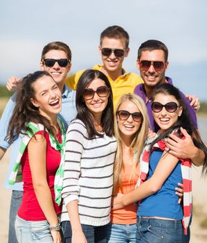 summer holidays, vacation, tourism, travel and people concept - group of happy friends having fun and hugging on beach