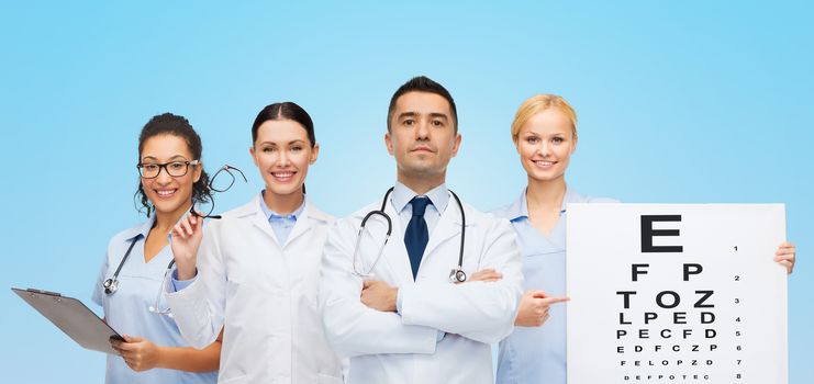 healthcare, eyesight, ophthalmology, people and medicine concept - group of doctors with eye chart and glasses over blue background