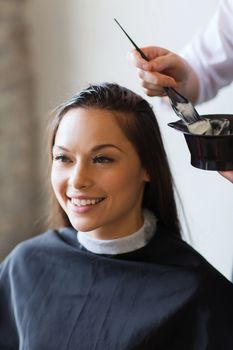 beauty and people concept - happy young woman with hairdresser coloring hair at salon
