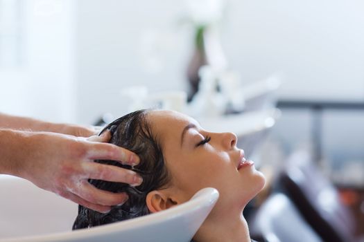 beauty and people concept - happy young woman with hairdresser washing head at hair salon