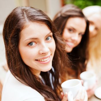 holidays and tourism concept - beautiful girls drinking coffee in cafe