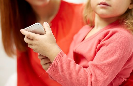 people, family and technology concept - close up of woman and little girl with smartphone