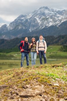 adventure, travel, tourism, hike and people concept - group of smiling friends with backpacks over mountains background