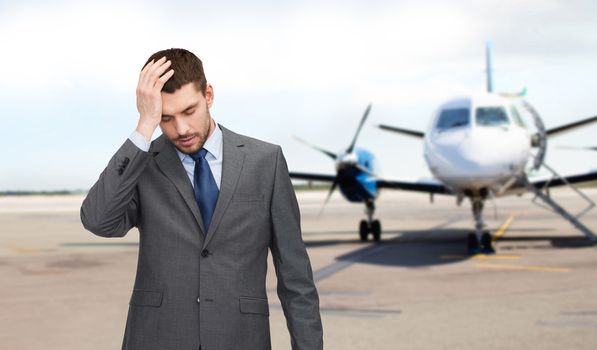 business, crisis, fail, people and travel concept - businessman having headache over airplane on runway background