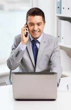 business, people and technology concept - smiling businessman with laptop computer calling on smartphone in office